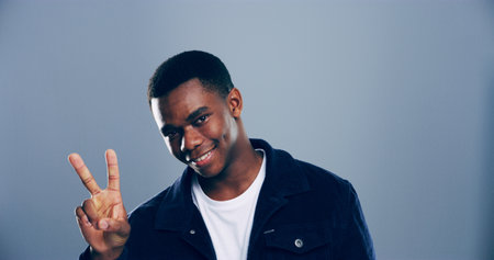 Portrait, space and black man with peace sign in studio with positive attitude, confidence and expression mockup. Grey background, face and African male model for cool gesture, fashion and symbolの写真素材