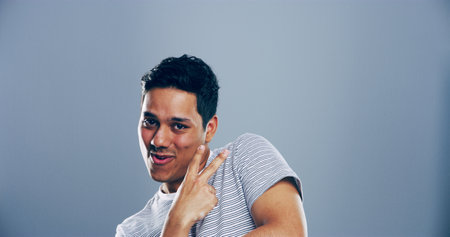 Portrait, space and man with peace sign in studio with positive attitude, confidence or facial expression. Grey background, casual mockup and male model for cool gesture, satisfaction or v symbolの写真素材
