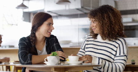 Cafe, friends and women with coffee, gossip and happy for conversation in morning, hangout and relax. Bonding, smile and listening to rumour in restaurant, weekend and break for people with teaの写真素材