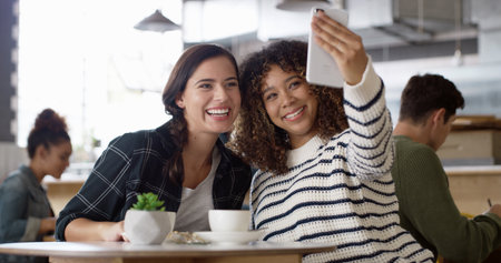 Cafe, friends and women with coffee, selfie and happy for bonding in morning, hangout and photography. Profile picture, laughing and smile for social media in restaurant, break and people with teaの写真素材