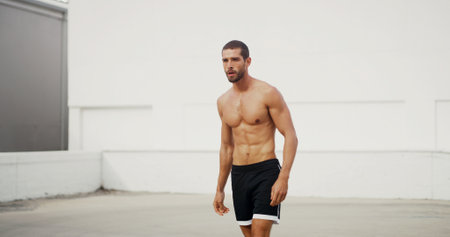 Man, shirtless and training in city, outdoor and workout for muscle growth in summer, health or wellness. Person, strong and resilience for development, performance or ready at urban club in Spainの写真素材