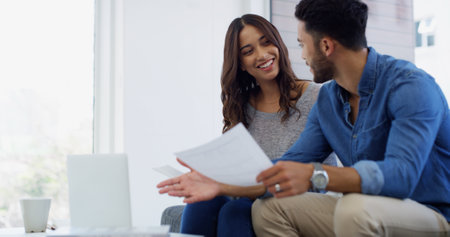 Laptop, discussion or couple with paperwork, planning or loan budget for salary for household bills. Financial, economy news or people with smile for investment, credit score report or savings auditの写真素材