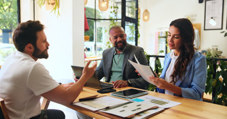 Planning, colleagues and people with documents, cafe or team with marketing proposal for campaign. Collaboration, smile and meeting with paperwork in coffee shop, brand manager or report for businessの写真素材