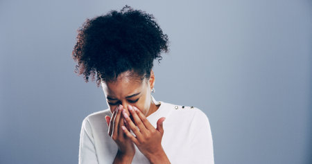 Crying, sad and woman in studio, grief and emotional reaction on blue background. Person, model and girl with mockup space, stress and sorrow with loss of relationship, mourning and broken heartの写真素材