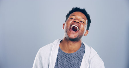 Crazy, man and happy for laugh in studio with confidence, joke and good mood on gray background. Space, African model and smile with fun personality for comedy, humor or funny reaction to memeの写真素材