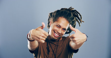 Portrait, thumbs up and man in studio, like and confidence on gray background. Face, happy person and model with hand gesture, agreement or icon with symbol, perfect and review with emoji or feedbackの写真素材