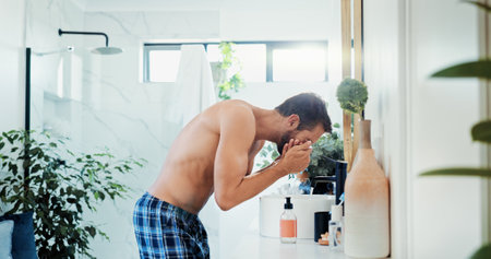 Man, tap and washing face with water for hygiene, grooming or morning routine in bathroom at home. Male person, rinse or cleanliness with faucet for facial treatment, skincare or disinfect at houseの写真素材