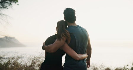 Fitness, couple and hug with back in nature, outdoor and training break at sunset. Exercise, man and embrace woman by sea to rest for body health, view and love together for wellness on mockup spaceの写真素材