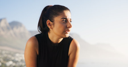 Outdoor, woman and tired with thinking for fitness, running challenge and fatigue with space. Nature, female person and runner with rest for exercise, cardio and exhausted with thoughts on breakの写真素材