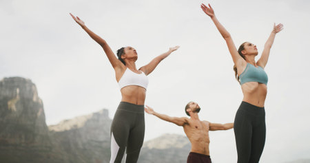 Friends, yoga and stretching with group in nature, man and women with breathing, wellness and mindfulness in morning. People, freedom and low angle with health, outdoor and mountains in summerの写真素材