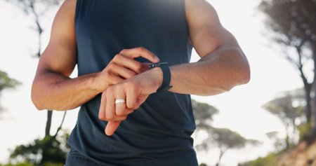 Man, hands and checking with smart watch for fitness tracking, performance or heart rate in nature. Closeup, active or male person with wristwatch for sport app, step counter or health and wellnessの写真素材