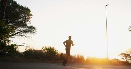 Man, fitness or running with sunset on mountain road for workout, exercise or cardio training. Back...