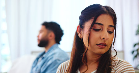 Sad, woman and conflict for couple, thinking and regret of marriage in home, argument or heartbreak. Lounge, contemplating and thoughtful of divorce in house, fight and people with dispute or tensionの写真素材