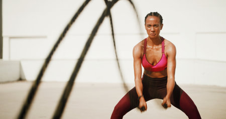 Fitness, workout and woman with battle ropes for intense training, exercise and health. Muscle, female bodybuilder and equipment for strength, fast and power for cardio challenge outdoor in cityの写真素材