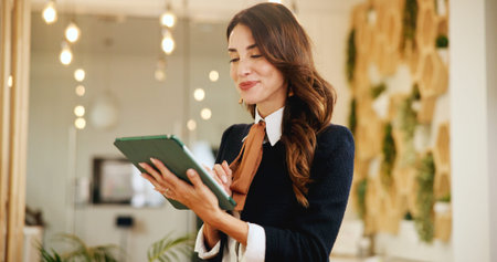 Reading, business woman and tablet in hotel for online booking, reservation schedule or information update. Digital technology, happy worker and communication with concierge typing on hospitality appの写真素材