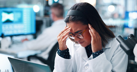 Scientist, woman and headache with stress in laboratory for medical research with laptop, burnout or brain fog. Person, computer and clinical trial with migraine, pain or exhausted with pharma studyの写真素材