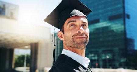 City, graduation and thinking with man student outdoor for celebration or education event. Future, scholarship and vision with happy college or university graduate in urban town for milestoneの写真素材