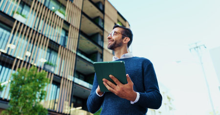 Thinking, businessman and research with tablet in city, realtor and project for property development. Below, real estate agent and inspiration with smile for online review, listing website or walkingの写真素材