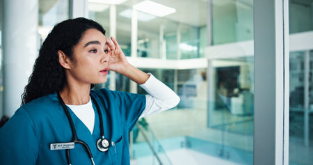 Frustrated woman, nurse and headache with window for fail, mistake or bad news at hospital. Female person, anxiety or disappointment with loss, pain or depression for negative procedure or resultsの写真素材
