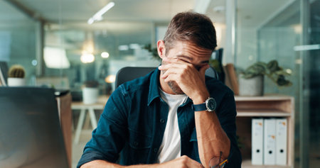 Man, headache and stress at startup with laptop, burnout or fatigue with deadline in modern office. Person, migraine and frustrated with eye pain, tired and glasses with mistake at creative agencyの写真素材
