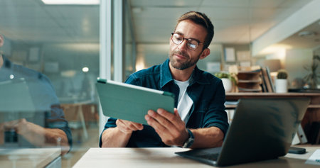 Tablet, glasses and laptop with business man in office for planning, ui designer and app review. Developer solutions, client feedback and research with person in agency for project idea and startupの写真素材