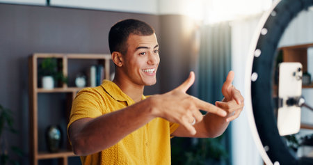 Man, influencer and social network with ring light in home for live stream, video or post with emoji. Person, selfie and happy with icon for chat, audience or mobile app for content creation in houseの写真素材