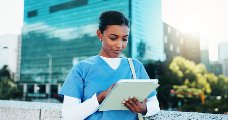 Medical, student and woman with tablet outdoor for education, course or wellness email. Digital technology, city and healthcare nurse reading schedule, exam results or information at college campusの写真素材