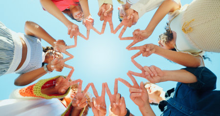 Blue sky, below and hands of people with peace sign for support, solidarity and community outdoors. Diversity, students and group of friends with emoji in circle for school, university and collegeの写真素材