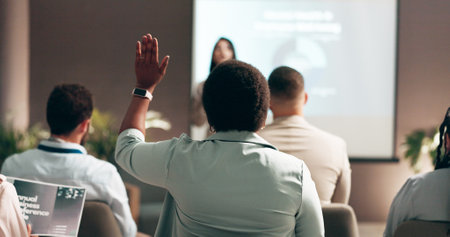 Business people, seminar and presentation with audience, question and interaction for feedback or engagement. Group, speaker and back of employee with hand raised for proposal or speech at conventionの写真素材