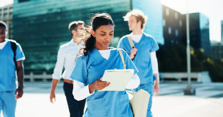 Medical, nurse and woman with tablet in city for education, learning or wellness email. Digital technology, outdoor and healthcare student reading schedule, exam results or travel to college campusの写真素材