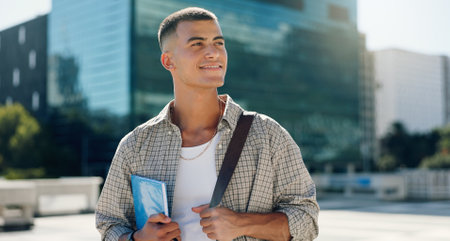 Happy, student and man in city thinking with books for travel to university, college and school campus. Smile, inspiration and person with backpack in town for future education, learning or knowledgeの写真素材