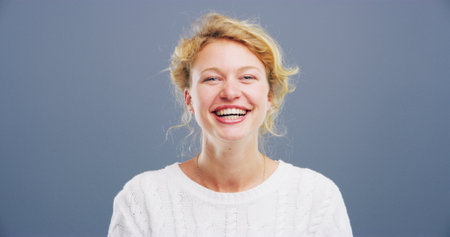 Portrait, woman and comedy with laughing in studio, funny memory and joke with mockup space. Confident model, female person and happiness with humor by blue background, satisfaction or emoji reactionの写真素材