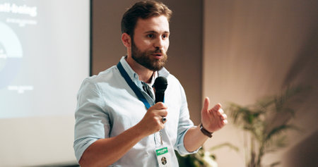 Businessman, development and presentation with speaker in conference room for wellness training. Education, forum speech and microphone with corporate coach on stage for public relations or seminarの写真素材