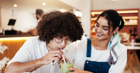 Couple, cafe and share drink on date for taste test, green juice and happy with bonding. Gen z people, smile and relationship in restaurant with relax, smoothie flavor and weekend break with supportの写真素材