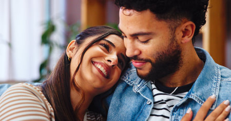 Home, hug and couple on sofa, love and bonding together with marriage, happiness and care. Embrace, apartment and man with woman, calm and resting with romance, relationship and relax in living roomの写真素材