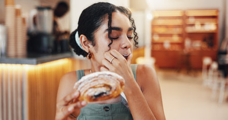 Cafe, happy and woman bite pastry eating for breakfast with snack, meal and hungry with craving. Coffee shop, restaurant and person with croissant, baked confectionery and delicious food for dessertの写真素材