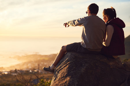 Couple, rock and outdoor with relax on cliff or point for view, adventure and bonding in nature or environment. Man, woman and together on mountain for fresh air, peace and horizon with love on trip.の写真素材