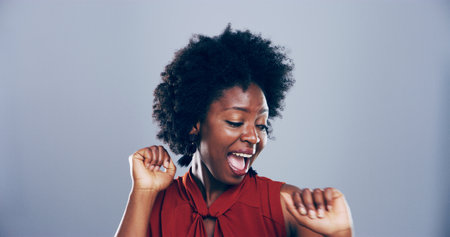 Dance, energy and smile of black woman in studio for celebration, clubbing or party fun. Afro, moving and music with excited African person on gray background space for beat, choreography or rhythmの写真素材