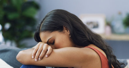 Sofa, exhausted and woman with depression in home for mental health, anxiety or loneliness in living room. Sad, low energy and female person with guilt and fatigue for breakup in lounge at apartment.の写真素材