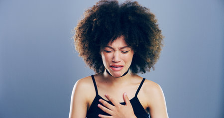 Crying, sad and woman with depression, studio and emotional reaction on blue background. Person, model and girl with mockup space, stress and grief with loss, mourning and broken heart with deathの写真素材