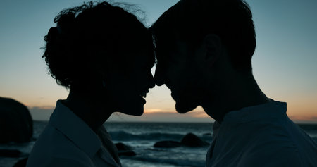 Forehead touch, beach and silhouette of couple at sunset for bonding, relationship and relax on weekend. Dating, travel and man and woman by ocean for romance on holiday, vacation and love in natureの写真素材