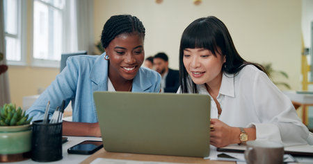 Business women, laptop and smile in office for feedback, advice or problem solving. Accountant team, collaboration or tech in agency for training, discussion and assistance with learning softwareの写真素材