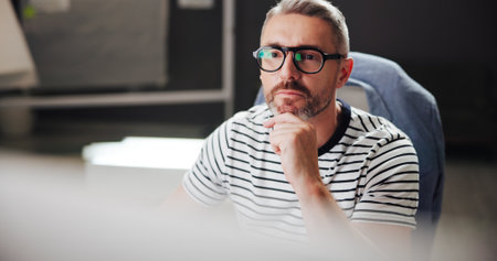 Online, night and mature man with computer, office and creative for web design with software or reading. Overtime, graphic designer and person with glasses in business, deadline and tech for projectの写真素材