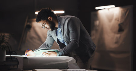 Businessman, architect and writing with tablet on blueprint for construction planning or building design. Man, civil engineer or working late with paper or technology at night for project deadlineの写真素材
