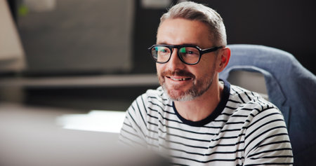 Office, mature businessman and smile with computer for developer, software update and research info. Night, male person and web designer with glasses reflection for digital agency, ux review and seoの写真素材