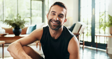 Portrait, happy and man in living room, fitness and healthy in home, exercise and athlete with sportswear. Morning, routine and person on break for workout, wellness and smile in lounge in Canadaの写真素材