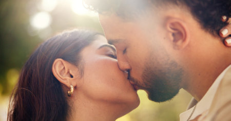 Hug, kiss and romance for couple, outdoor and bonding for commitment in relationship and affection. Park, man and woman on date with love, care and celebration for anniversary, nature or peopleの写真素材