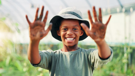 Portrait, dirty hands and black child in garden, palms and nature with ecology, vegetables and smile. African person, outdoor and boy with soil, pride and environment with agriculture and muddyの写真素材