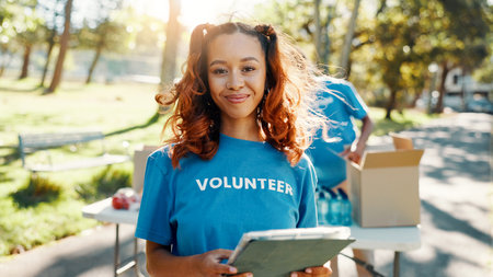 Outdoor, woman and portrait of volunteer with tablet for checking food drive donation list. Confident, nature and female NGO worker with digital technology in park for nonprofit or charity event.の写真素材