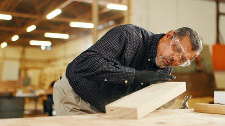 Mature carpenter, wood and blow dust for project, process or manufacturing furniture. Woodwork, man and remove sawdust shavings for hobby craftsman in construction industry or diy renovations productの写真素材